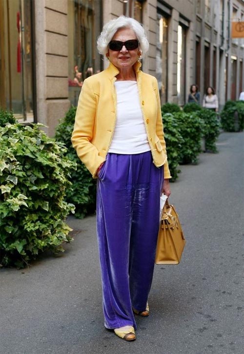 Женщина в возрасте в бархатных брюках и желтом жакете